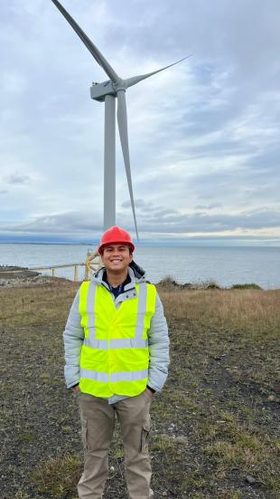 IDCORE Research Engineer - Yusril Fatahilmi with a wind turbine in the background