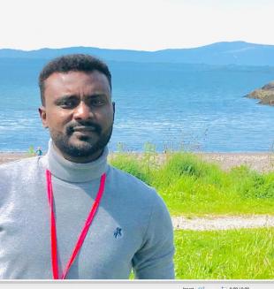 Mujahid Elobeid portrait photo with countryside and mountains in the background