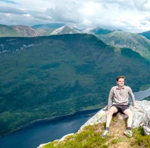 Nicholas Kell sitting atop a mountain in Scotland