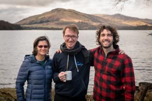 group photo of three IDCORE members with sea and mountains in background