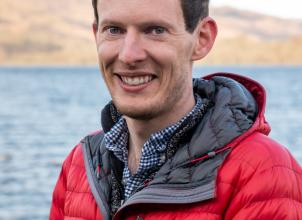 Jonathan Glasspool headshot, weating red bubble jacket