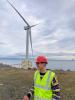 IDCORE Research Engineer, Thomas Page, with a wind turbine in the background
